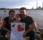 A family poses with a Clean Water sign on the shore of Lake Julian.