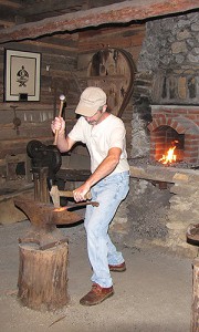 Barry Stiles, curator of the Foxfire Museum, demonstrates blacksmithing skills in a traditional cabin maintained by the Foxfire Fund.