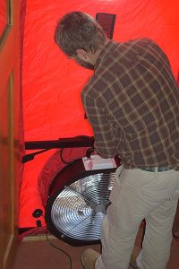 John Kidda, a home energy contractor, prepares a blower door test at Sean Dunlap’s home. Photo by Eliza Laubach