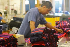 A worker-owner arranges fabric at the Opportunity Threads plant in Morganton, N.C.  Photo by Willa Johnson