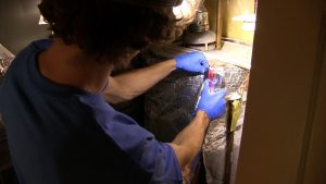 Harper Robinson of Conservation Pros connects a water heater blanket by applying insulation tape.