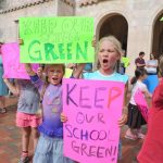 Two female students holding signs that say "Keep our school green"