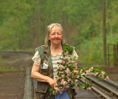 Carol Judy carries branches of flowers in Bell County, Ky. Photo by Joanne Golden Hill.