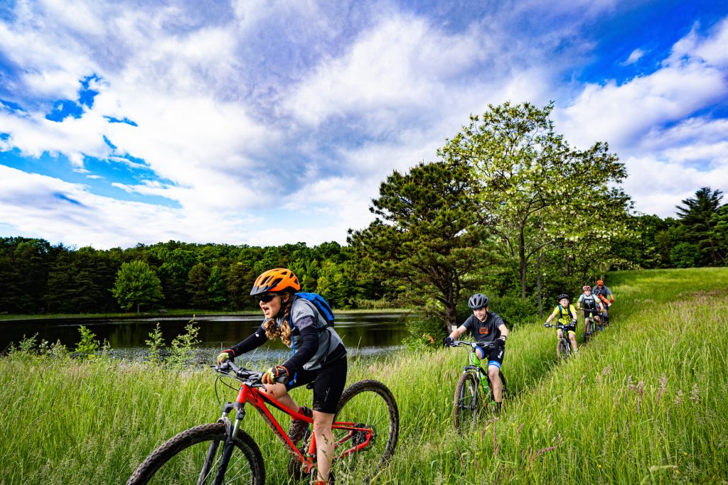 Bike riders on a trail in front of a body of water