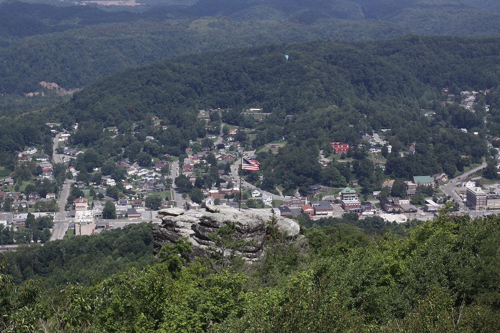 View of small town surrounded by mountains, American flag in foreground