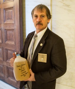 State Delegate Mike Manypenny (D-Taylor Co.) holds a jug of contaminated water he received from Dustin White. Manypenny accepted the jug and said he will have it analyzed. Photo by Paul Corbit Brown