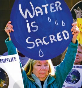 A woman holds a sign during a the demonstration against the Dakota Access Pipeline in Huntington, W.Va. Photo by  Chad Cordell