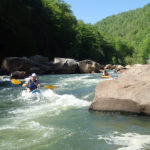 Two kayakers navigate a rapid