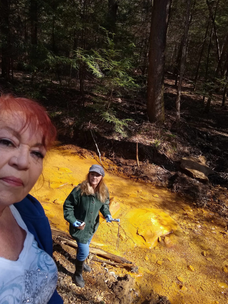 Women stand by bright yellow creek