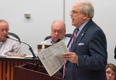 Mayor holds a newspaper at the podium