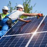 two men install solar panels