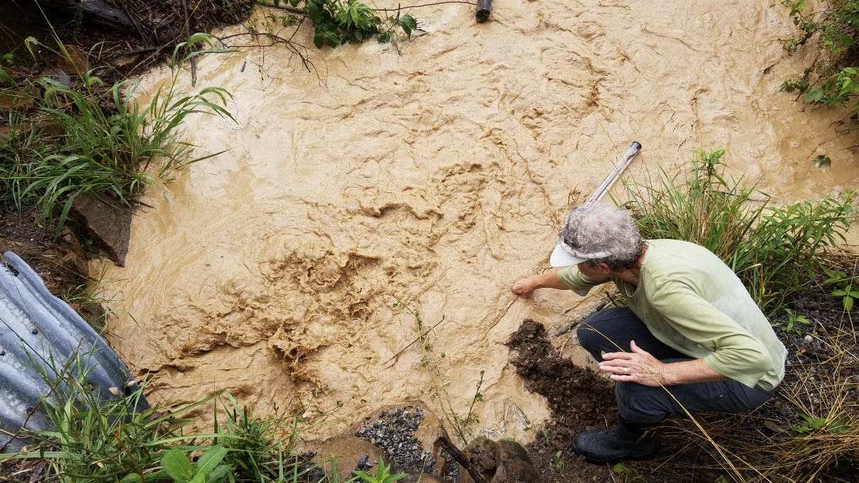 Nancy Bouldin takes a water sample from a culvert near Blue Lick Creek in 2018 after heavy rain washed sediment from MVP construction into nearby waterways. Photo by Russell Chisholm.