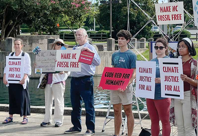 Photo of people at an event holding signs like Keep NC Frack Free and Climate Justice for All