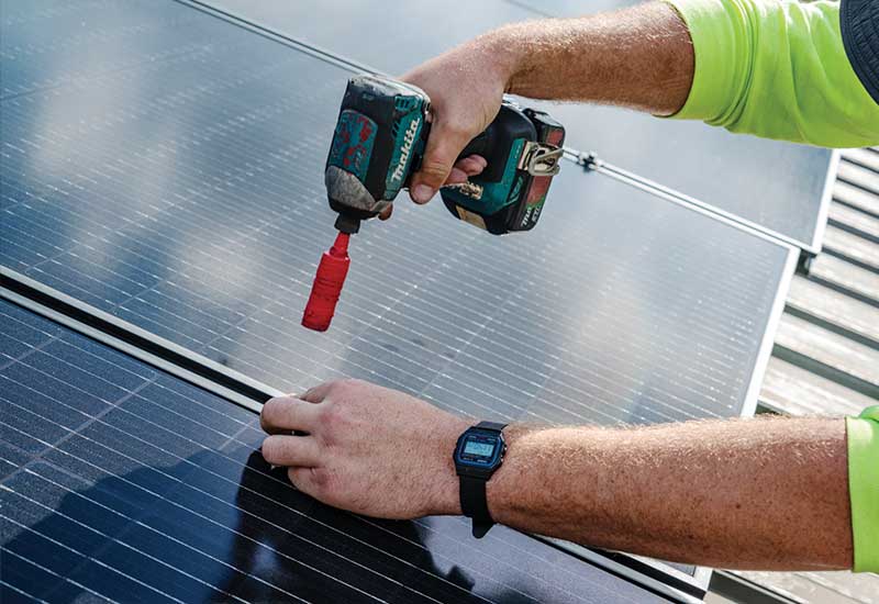 A person's hands using a tool to install solar panels