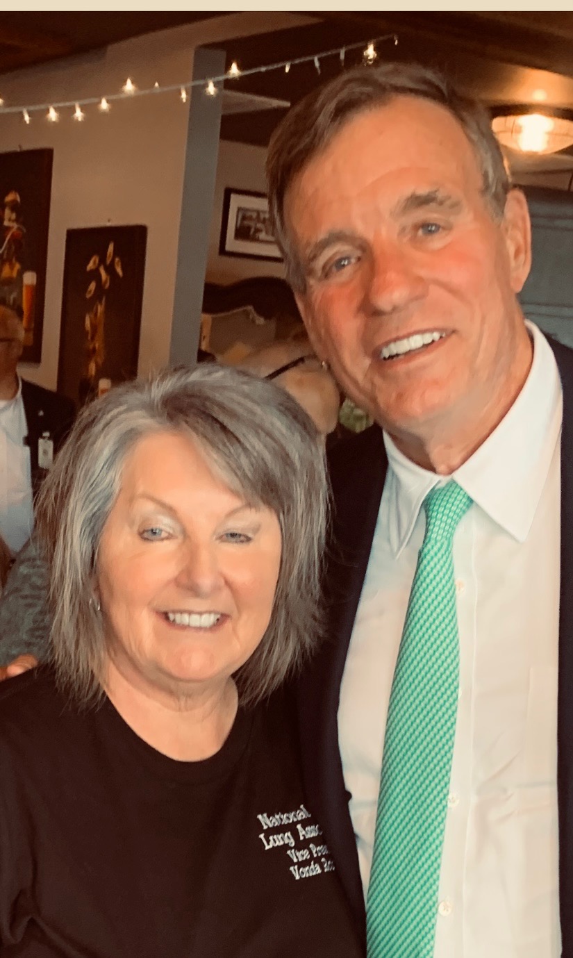woman in black shirt with National Black Lung Association lettering beside man in a suit and tie