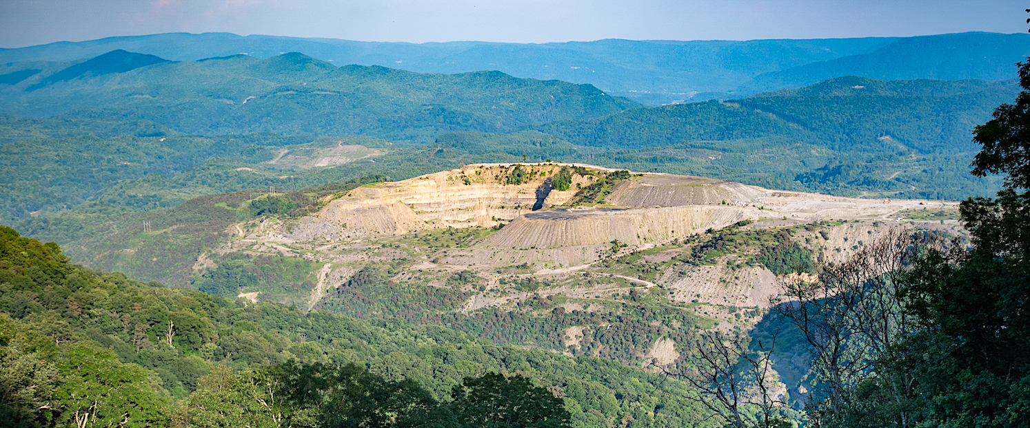surface mine surrounded by green mountains