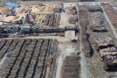 Aerial view of wood piles outside at a wood pellet processing plant.