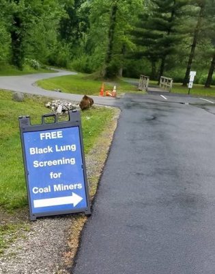A blue sign with white lettering reads, "FREE Black Lung Screening for Coal Miners."