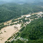 An aerial photo shows muddy water overflowing the banks of a river and flooding a town in a Kentucky valley.