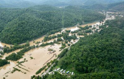 An aerial photo shows muddy water overflowing the banks of a river and flooding a town in a Kentucky valley.