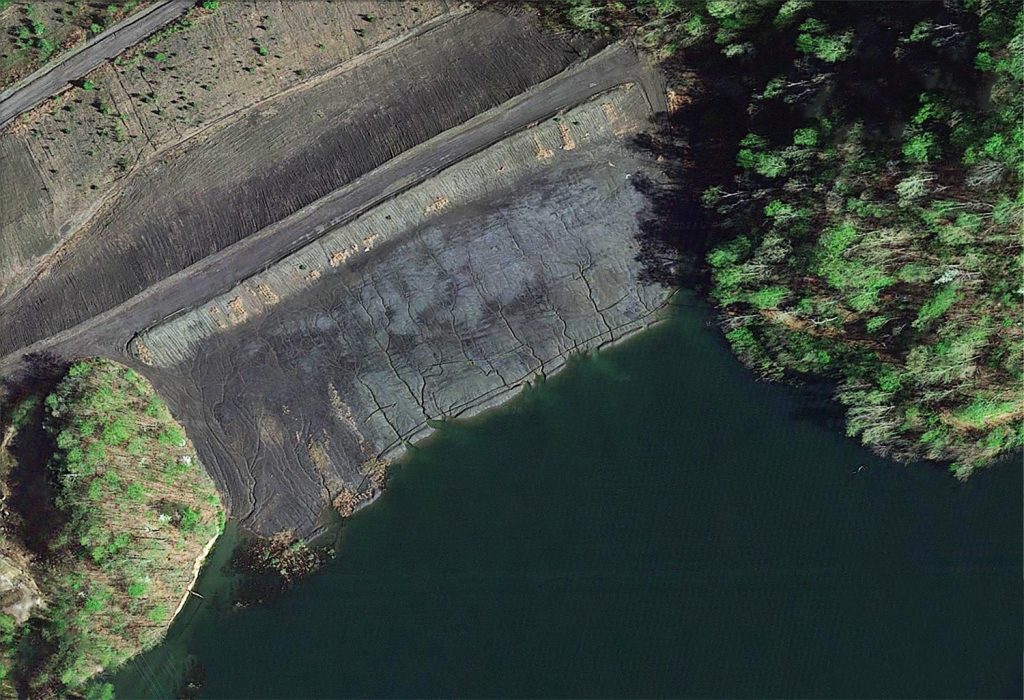 This aerial satellite photo looks down on a fissured earthen dam.