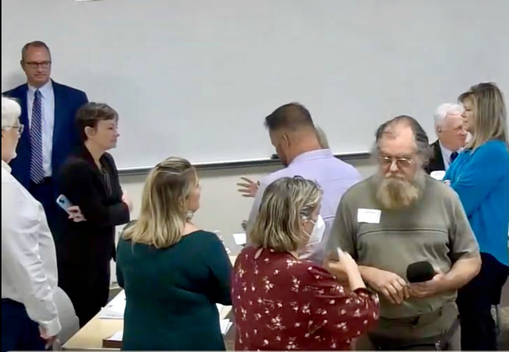 People stand in a room with a whiteboard covering the wall behind them