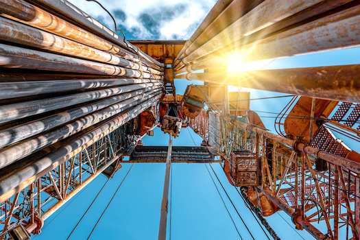 A vertical view of the center of a fracking drill with blue sky above it.