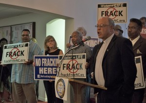 Rev. Hairston, president of the Stokes County, N.C., NAACP, speaks at an event to bring attention to disproportionate environmental threats in low-income communities of color. At left, a concerned resident holds a sign asking for the state to designate Belews Creek as a high-priority coal ash cleanup site. 