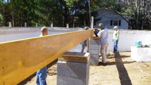 A group of volunteers for Ashe County Habitat for Humanity lays a timber frame on their first house, which was built with energy efficiency and alternative energy to lessen the burden of utility bills on people living in poverty.