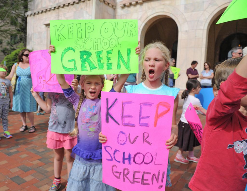 Two female students holding signs that say "Keep our school green"