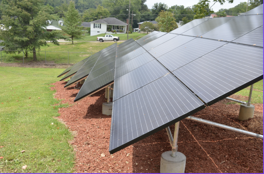 A row of solar panels installed on a lawn.