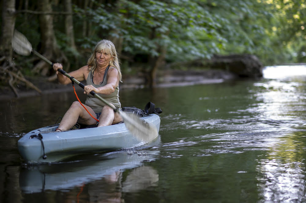 A woman with gray hair paddles a canoe