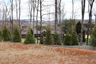 A pipeline trench is seen running across a yard with a house behind it.