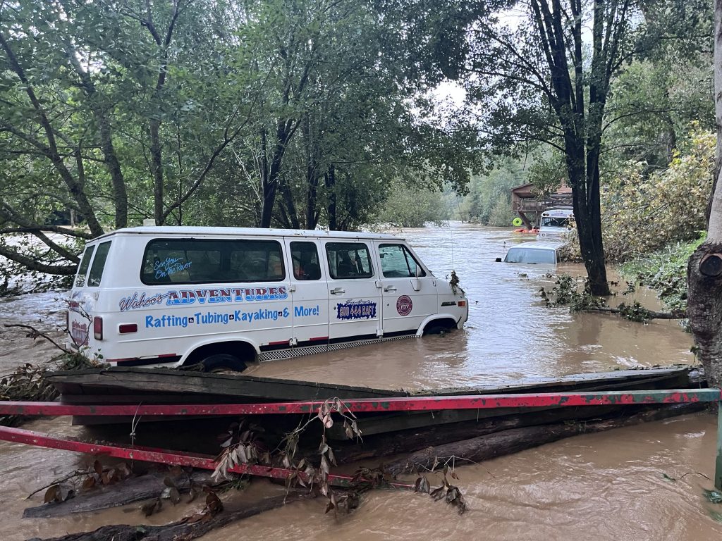 Muddy water surrounds vehicles along with piled up debris.