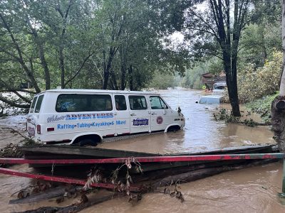 Muddy water surrounds vehicles along with piled up debris.