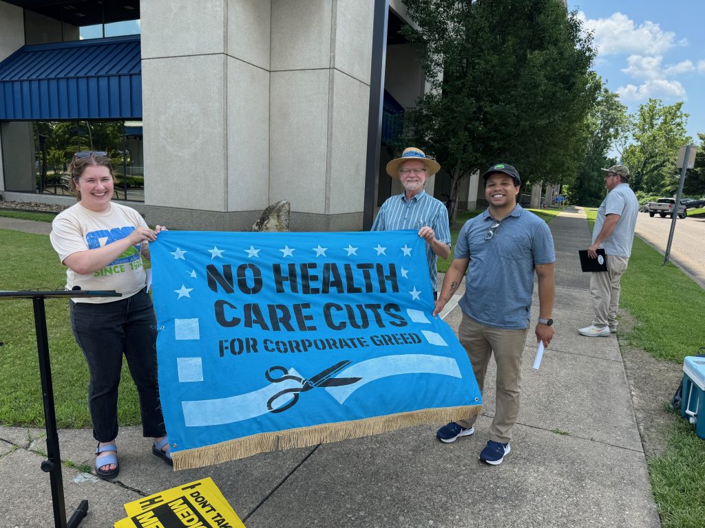 Speakers from West Virginia Center on Budget and Policy, West Virginia Citizen Action Group, and Appalachian Voices poise with flag outside of Senator Jim Justice's office at a press conference. Photo by Dan Radmacher.