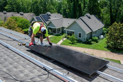 man on roof installing a solar panel