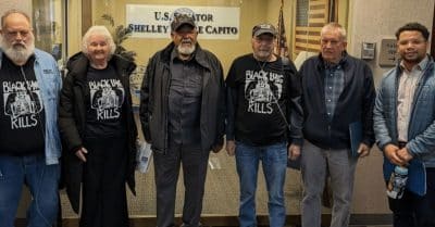 A group of Black Lung Association members stand in front of Shelley Moore Capito's office.
