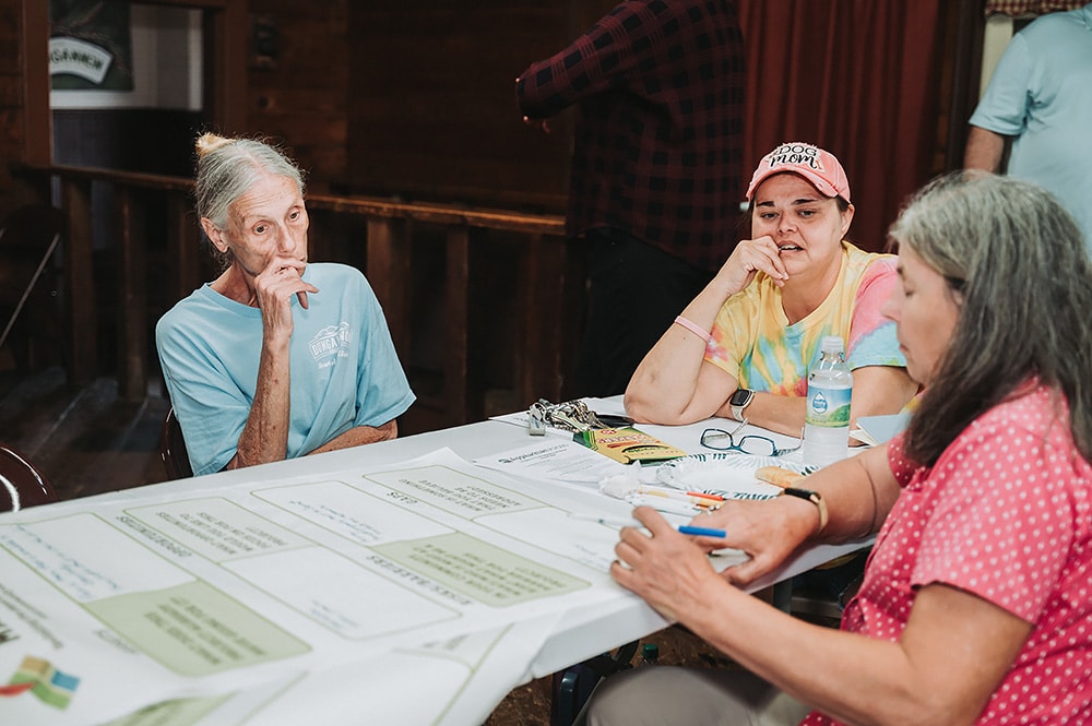 Three women sit talking about a table