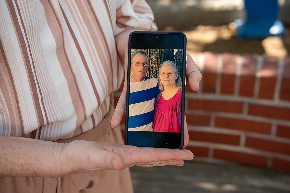 A woman holds a photo of her parents on her phone