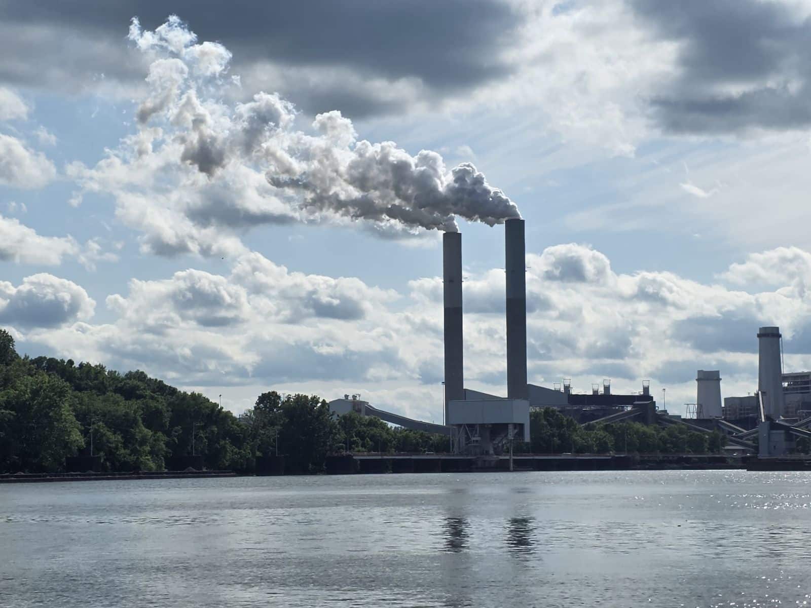 A power plant spews air pollution beside a river